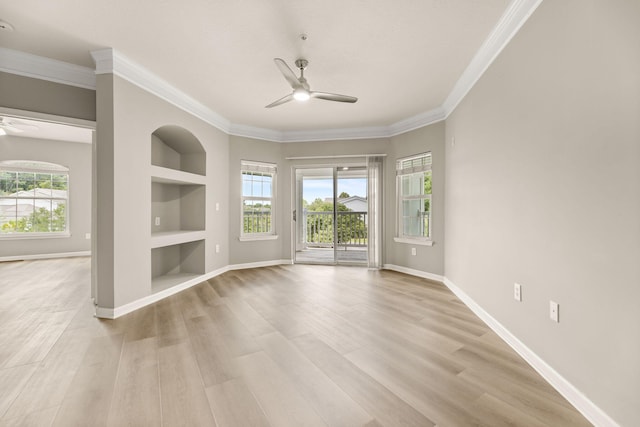 empty room with crown molding, built in features, ceiling fan, and light wood-type flooring