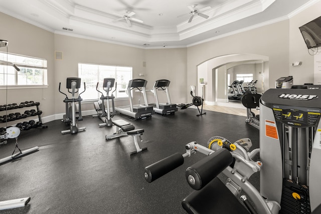 gym featuring a wealth of natural light, ornamental molding, a raised ceiling, and ceiling fan