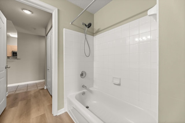 bathroom featuring wood-type flooring, a textured ceiling, and tiled shower / bath