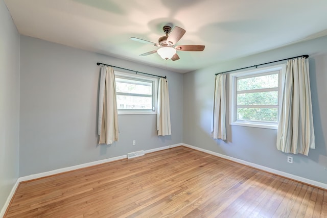 spare room featuring visible vents, a ceiling fan, baseboards, and light wood-type flooring
