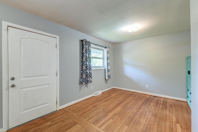spare room with baseboards, visible vents, and light wood-style floors