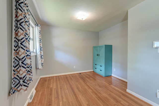 empty room featuring baseboards, visible vents, and light wood-style flooring