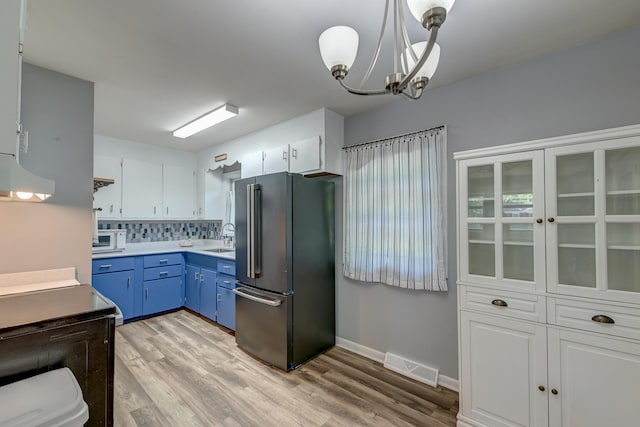 kitchen featuring blue cabinetry, visible vents, white microwave, high end fridge, and light wood-style flooring