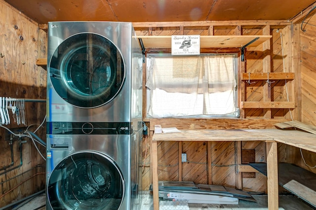 washroom with laundry area, stacked washer and dryer, and wood walls