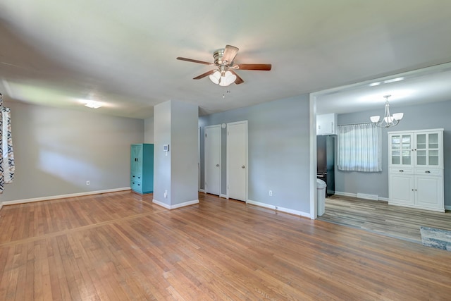 unfurnished living room with baseboards, light wood-style flooring, and ceiling fan with notable chandelier