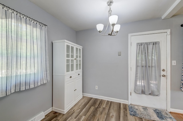 unfurnished dining area with an inviting chandelier, baseboards, and wood finished floors