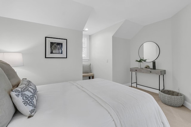 bedroom with lofted ceiling, light carpet, and baseboards