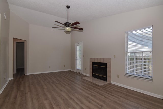 unfurnished living room with dark wood-type flooring, a textured ceiling, a fireplace, high vaulted ceiling, and ceiling fan