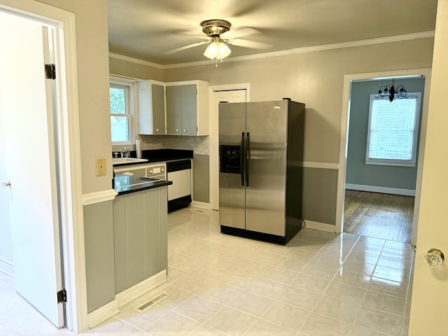 kitchen featuring stainless steel fridge with ice dispenser, backsplash, dishwashing machine, light tile patterned floors, and ceiling fan with notable chandelier