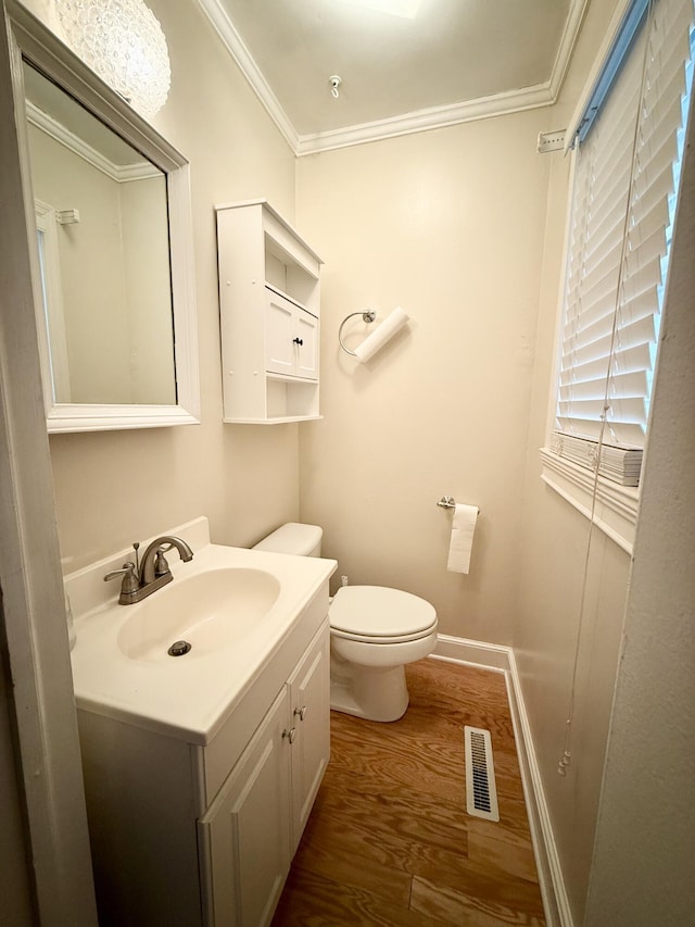 bathroom featuring vanity, hardwood / wood-style flooring, toilet, and ornamental molding