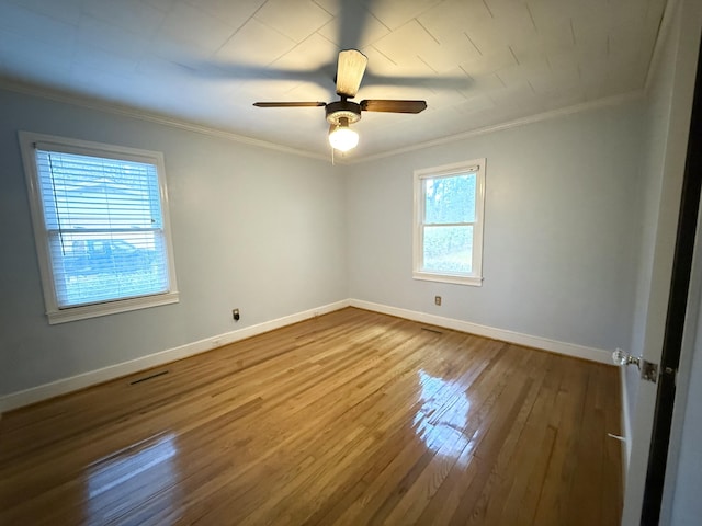 empty room with crown molding, plenty of natural light, ceiling fan, and hardwood / wood-style flooring