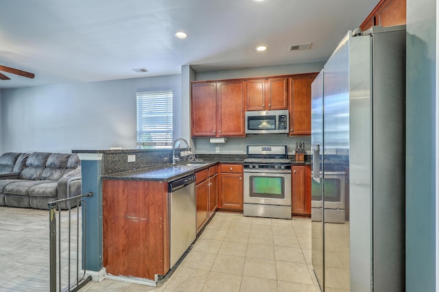 kitchen with a ceiling fan, a peninsula, open floor plan, a sink, and stainless steel appliances