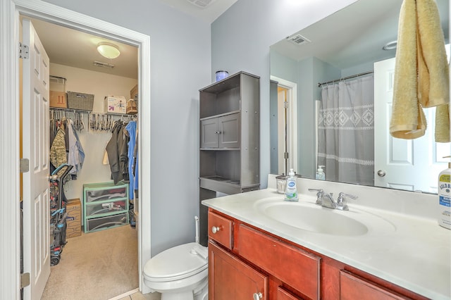 full bath featuring vanity, toilet, a spacious closet, and visible vents