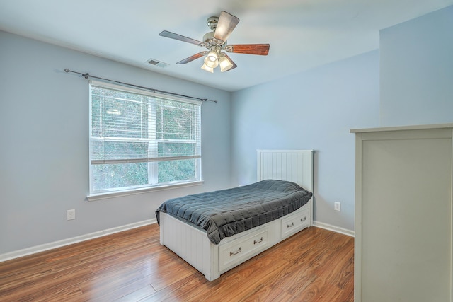 bedroom featuring baseboards, ceiling fan, wood finished floors, and visible vents