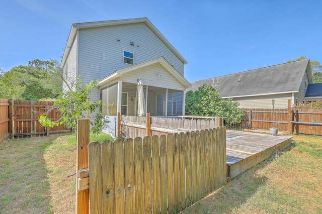 back of property with a lawn, a fenced backyard, and a deck