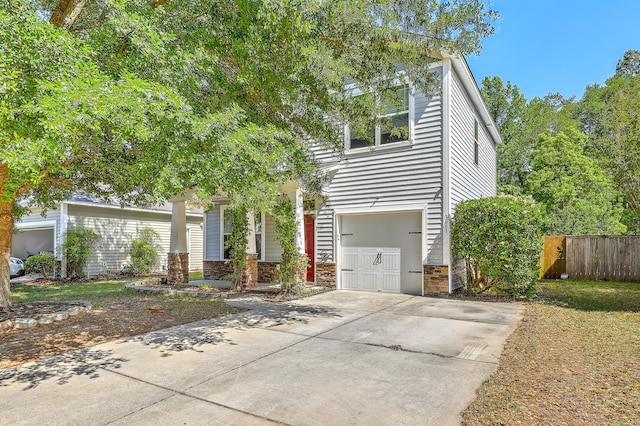 view of front facade featuring fence, an attached garage, concrete driveway, and stone siding