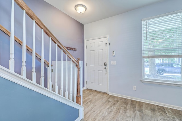 foyer with baseboards, wood finished floors, a wealth of natural light, and stairway
