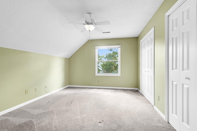 bonus room with light carpet, a textured ceiling, vaulted ceiling, and ceiling fan