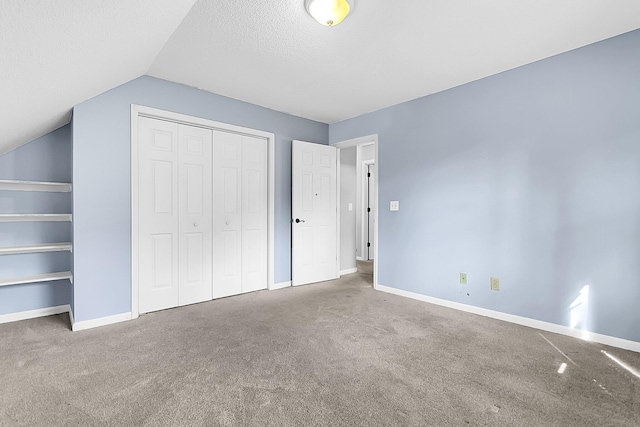 unfurnished bedroom with carpet flooring, a textured ceiling, and vaulted ceiling