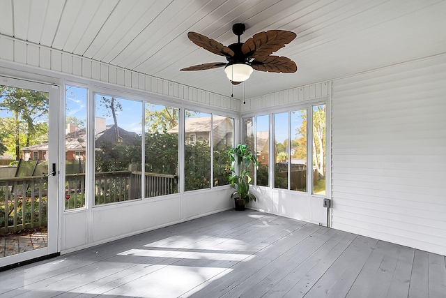 unfurnished sunroom featuring ceiling fan, plenty of natural light, and a mountain view