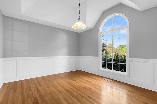 unfurnished room featuring lofted ceiling and hardwood / wood-style flooring