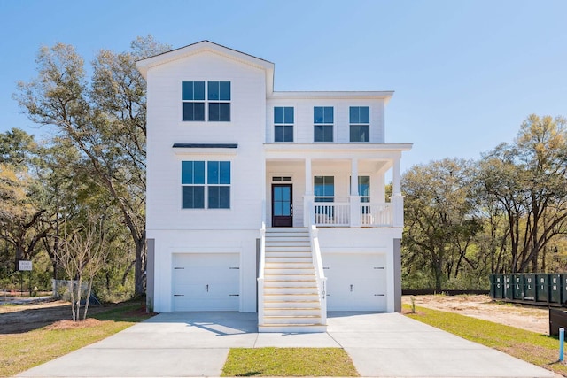 beach home with an attached garage, covered porch, stairway, and concrete driveway