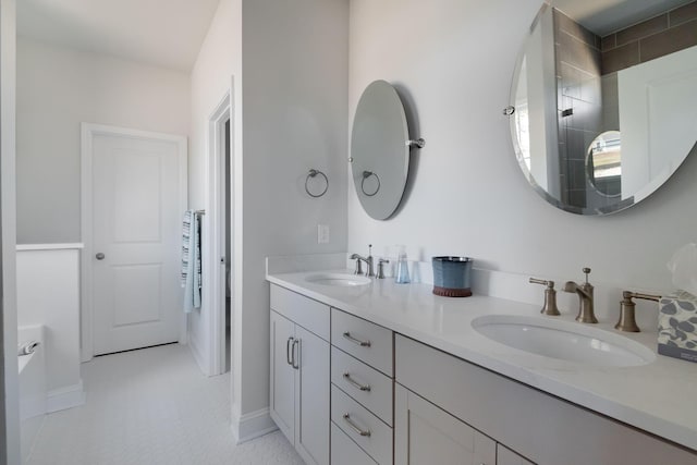 full bathroom featuring double vanity, baseboards, tiled shower, and a sink