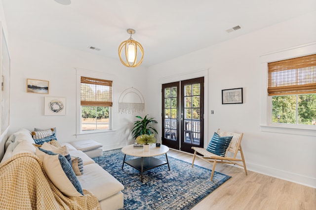 living room with plenty of natural light, light wood-type flooring, and french doors