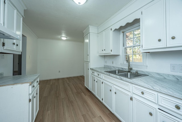 kitchen with a textured ceiling, light wood-type flooring, white cabinetry, and sink