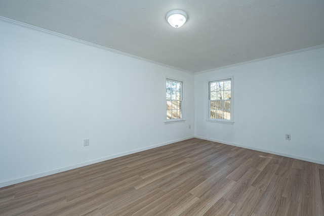 empty room featuring a textured ceiling, light hardwood / wood-style floors, and ornamental molding