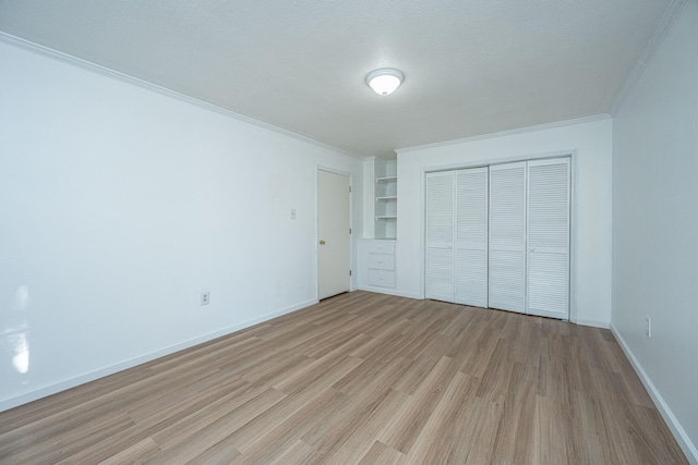 unfurnished bedroom featuring a textured ceiling, light wood-type flooring, a closet, and ornamental molding