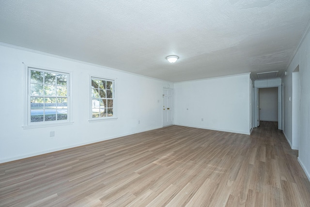 empty room with light hardwood / wood-style flooring, a textured ceiling, and ornamental molding