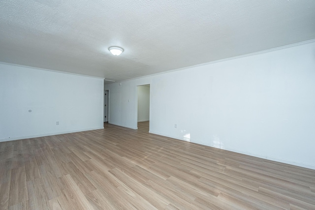 empty room with crown molding, a textured ceiling, and light wood-type flooring