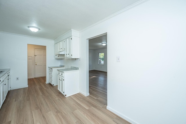 kitchen featuring white cabinets, a textured ceiling, light wood-type flooring, and crown molding