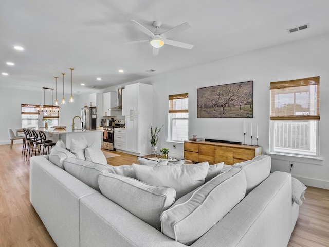 living room featuring light hardwood / wood-style floors, a wealth of natural light, and ceiling fan