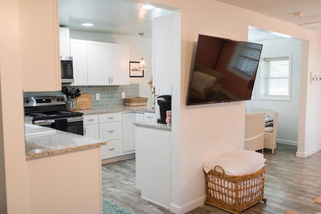 kitchen with stainless steel appliances, white cabinetry, tasteful backsplash, and light hardwood / wood-style floors