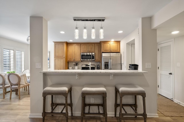 kitchen with decorative backsplash, a breakfast bar area, stainless steel appliances, and kitchen peninsula