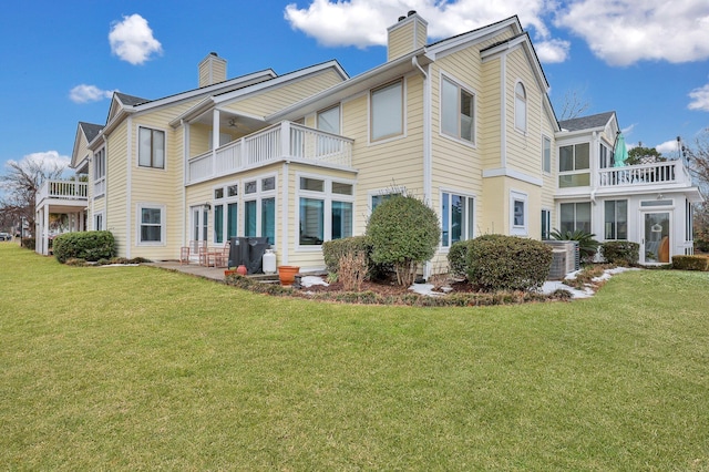 rear view of property featuring a balcony and a yard