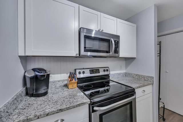 kitchen with stainless steel appliances, wood-type flooring, and white cabinets