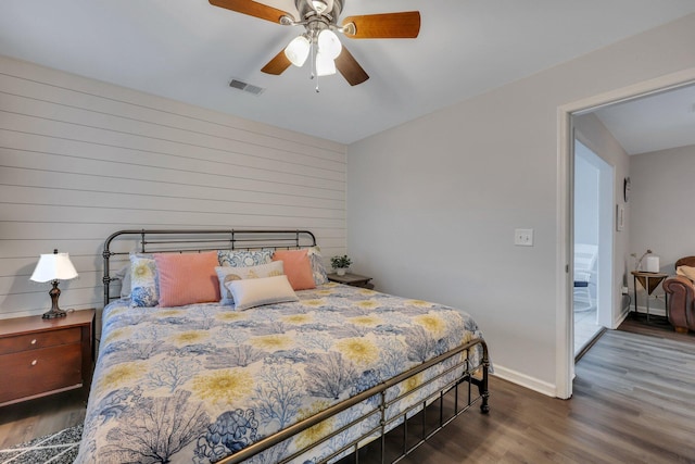 bedroom featuring dark wood-type flooring, ceiling fan, and wood walls