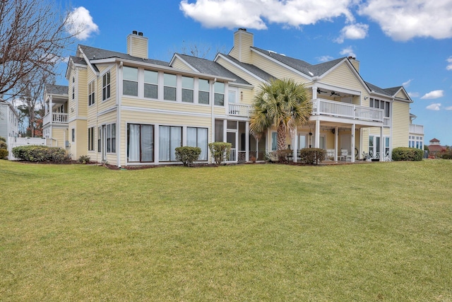 rear view of house with a balcony and a yard