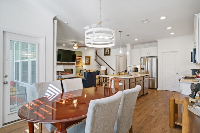 101 Caleb Ct, Ladson, SC 29456 - dining room with a ceiling fan, a warm lit fireplace, dark wood finished floors, recessed lighting, and crown molding
