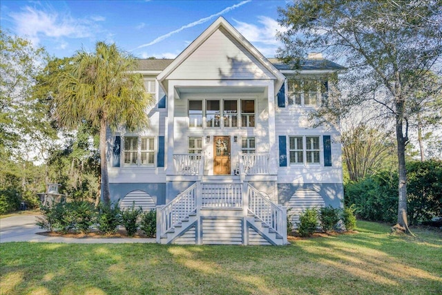 coastal inspired home with a balcony, a front lawn, and a porch