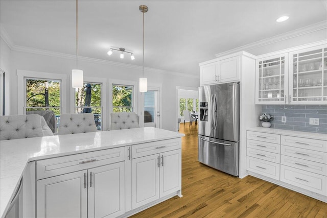 kitchen featuring crown molding, light hardwood / wood-style flooring, stainless steel fridge with ice dispenser, decorative light fixtures, and white cabinetry