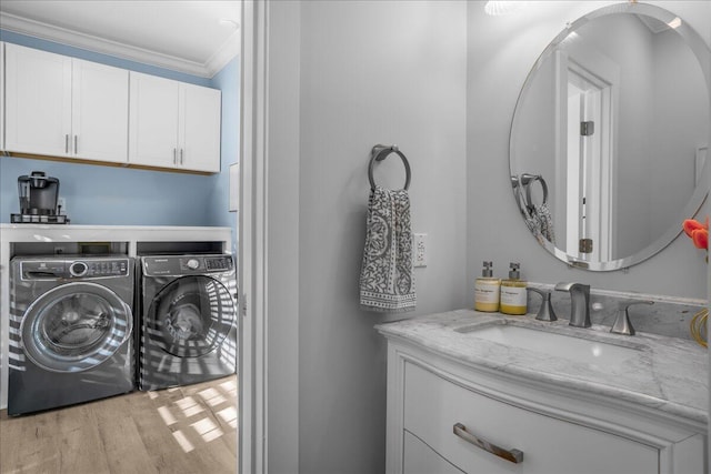 clothes washing area with separate washer and dryer, light hardwood / wood-style flooring, crown molding, and sink