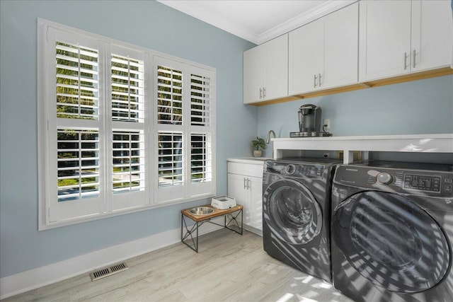 laundry area featuring washer and dryer, cabinets, light wood-type flooring, and crown molding