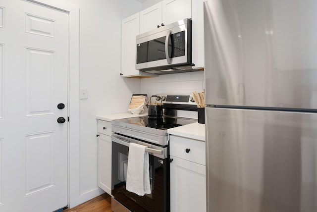 kitchen featuring backsplash, wood finished floors, appliances with stainless steel finishes, white cabinets, and light countertops