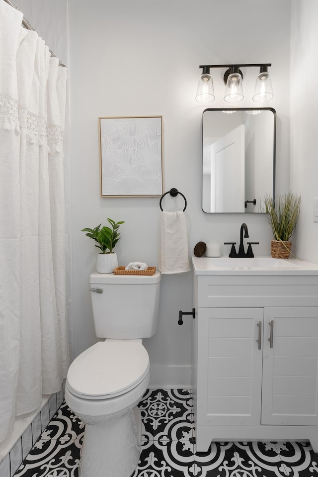 bathroom featuring vanity, a shower with shower curtain, baseboards, tile patterned floors, and toilet