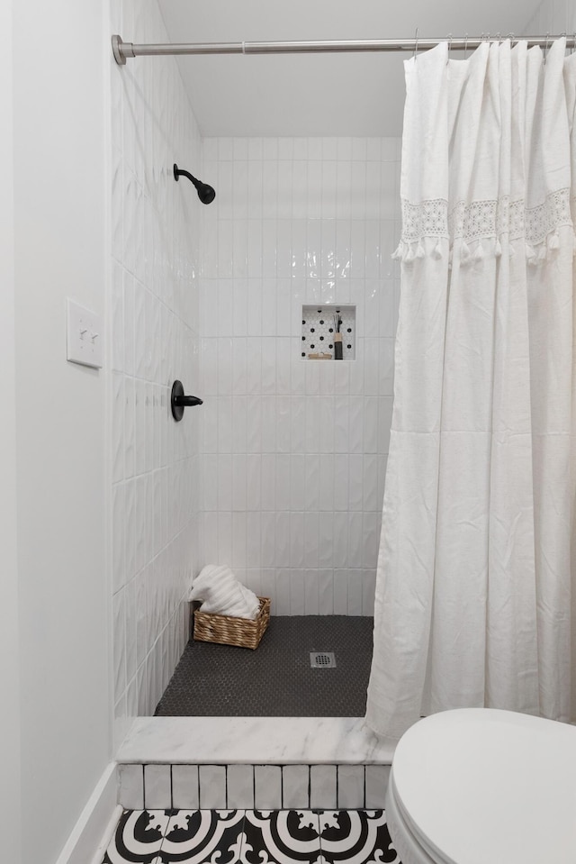 bathroom featuring a tile shower and toilet