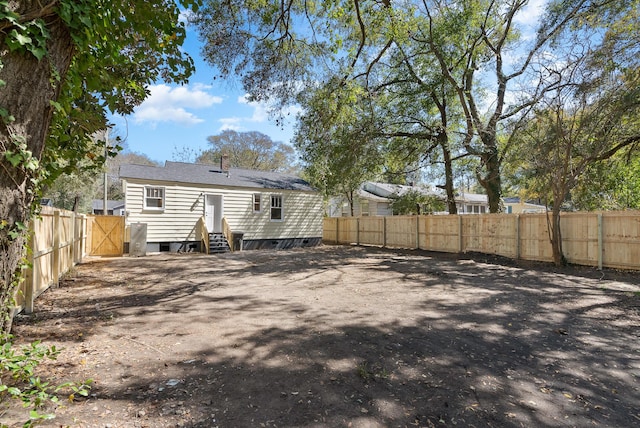 back of house with entry steps, a fenced backyard, and a chimney